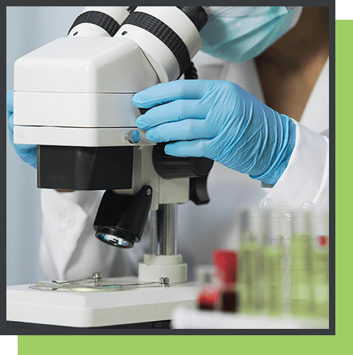 A person in gloves looking through a microscope.