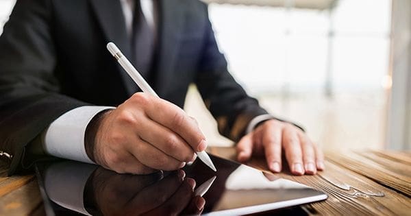 A man in a suit writing on paper.