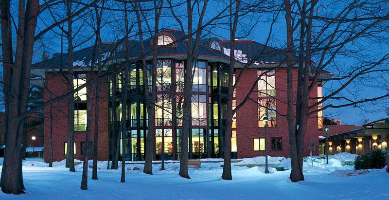 A building with trees in the background and snow on the ground.