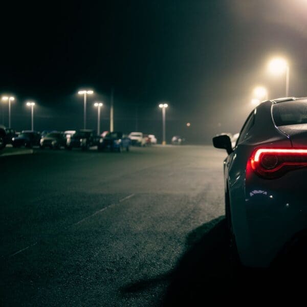 A car parked in the middle of a parking lot at night.