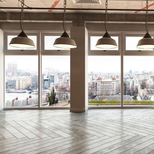 A room with three windows and two lights hanging from the ceiling.