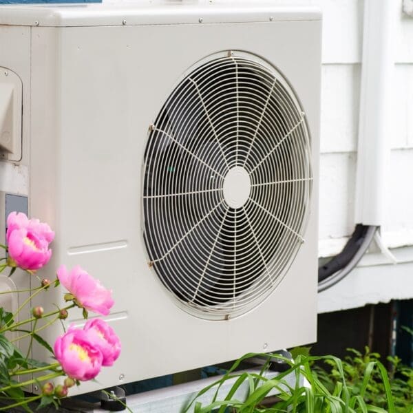 A white air conditioner sitting outside of a house.