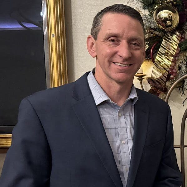 A man in a suit standing next to christmas decorations.