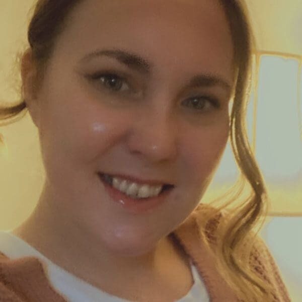 A woman with long hair and white shirt smiling.