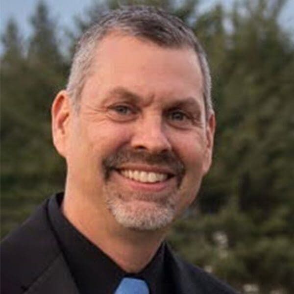 A man in a suit and tie smiling for the camera.